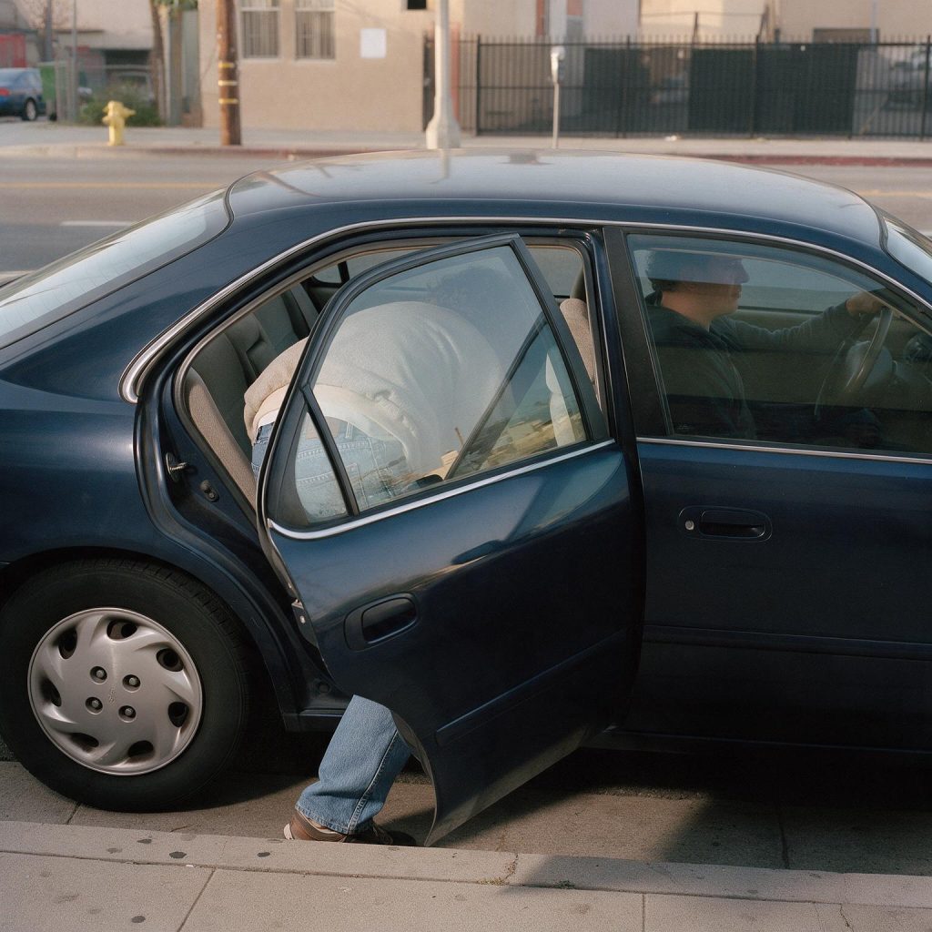 Passenger entering a sedan at a California curb