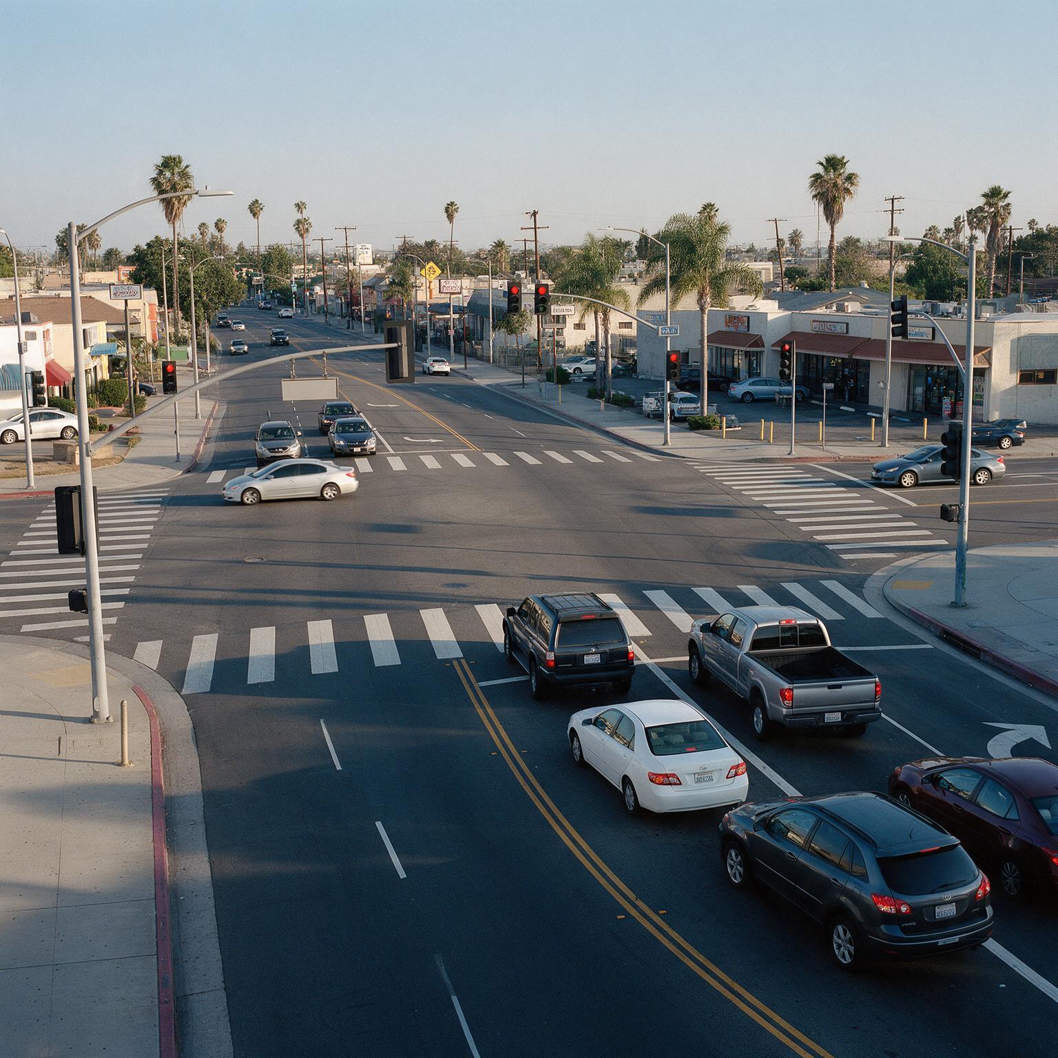 Cars approaching a California intersection with traffic lights and marked crosswalks